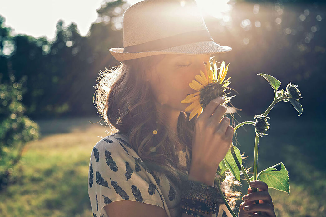 Donna annusa un girasole – simbolo di un’economia energetica rinnovabile e vicina alla natura.