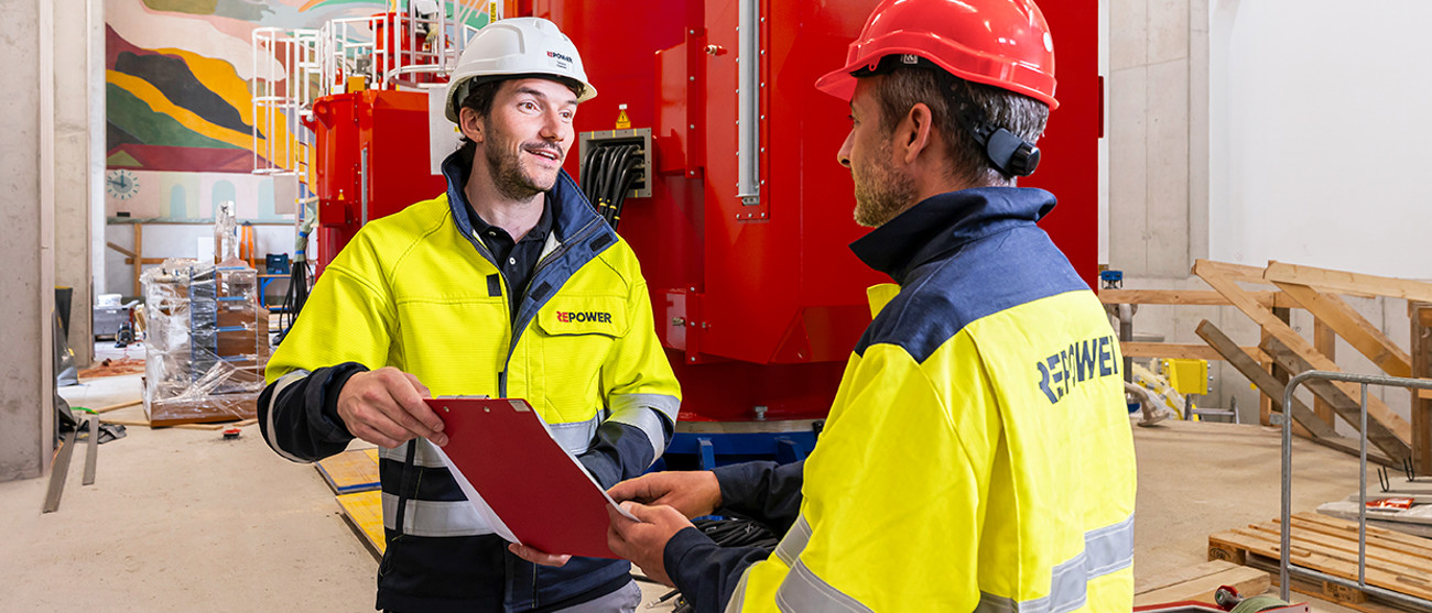 Zwei Repower-Mitarbeitende mit Helm und Weste im Kraftwerk – Jahresergebnis durch Handel ausserordentlich gut.