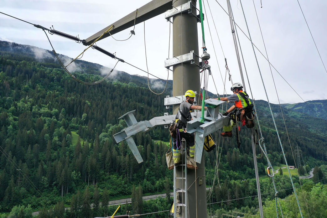 Netzelektriker bei Reparaturarbeiten auf einem Strommasten.