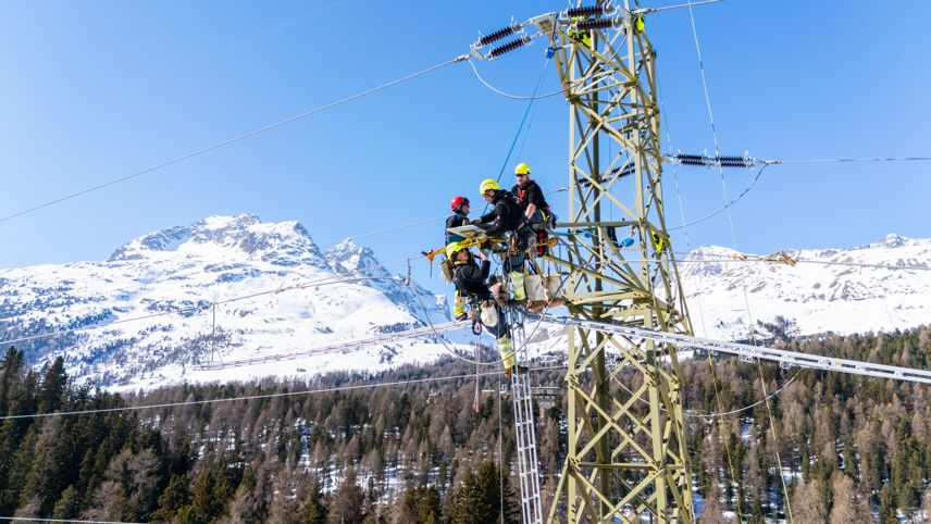 Monteure arbeiten auf Hochspannungsmast und tauschen Isolatoren