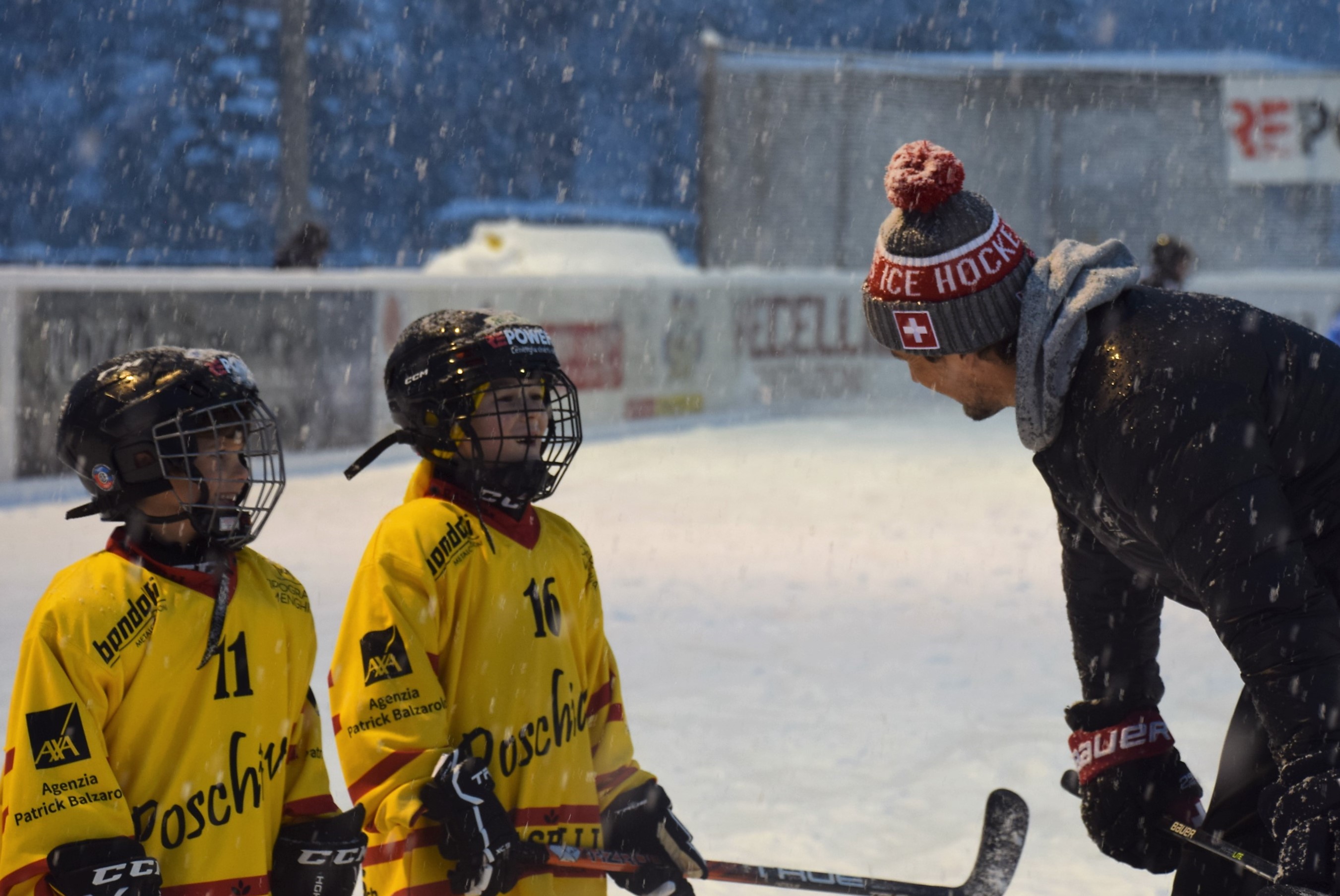 Eishockeyspiel im Schnee: Trainer gibt Anweisungen an Kinder auf dem Eis unter winterlichen Bedingungen.