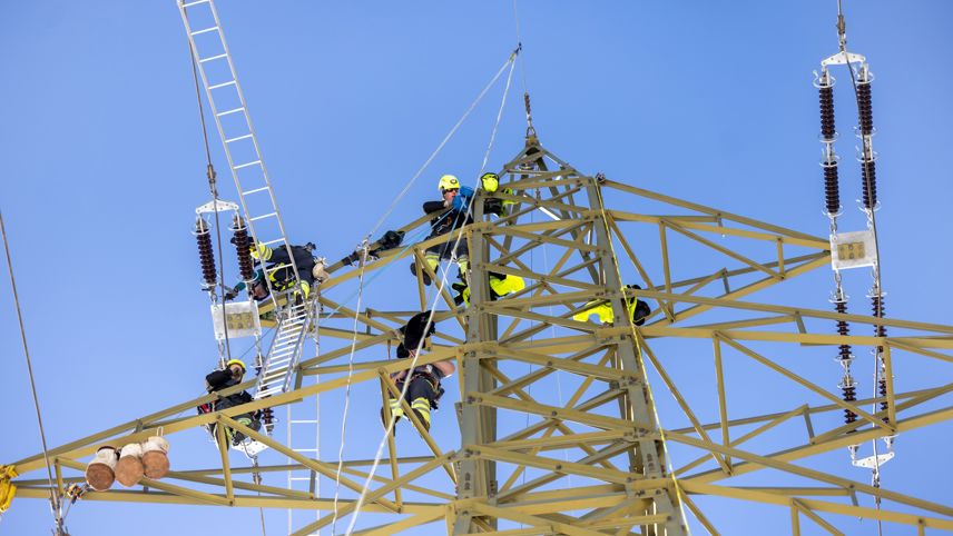 Monteure arbeiten am Hochspannungsmast und ersetzen Isolatoren